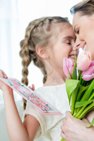 happy mother hugging daughter with postcard on mother's day