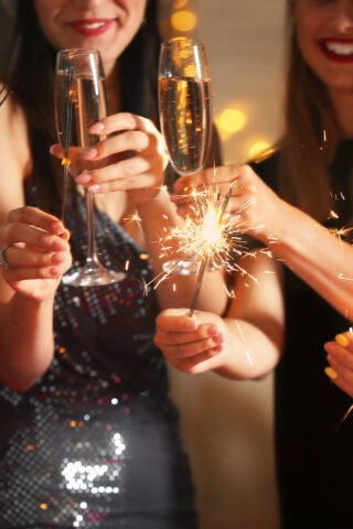 Happy women with Christmas sparklers and glasses of champagne at party